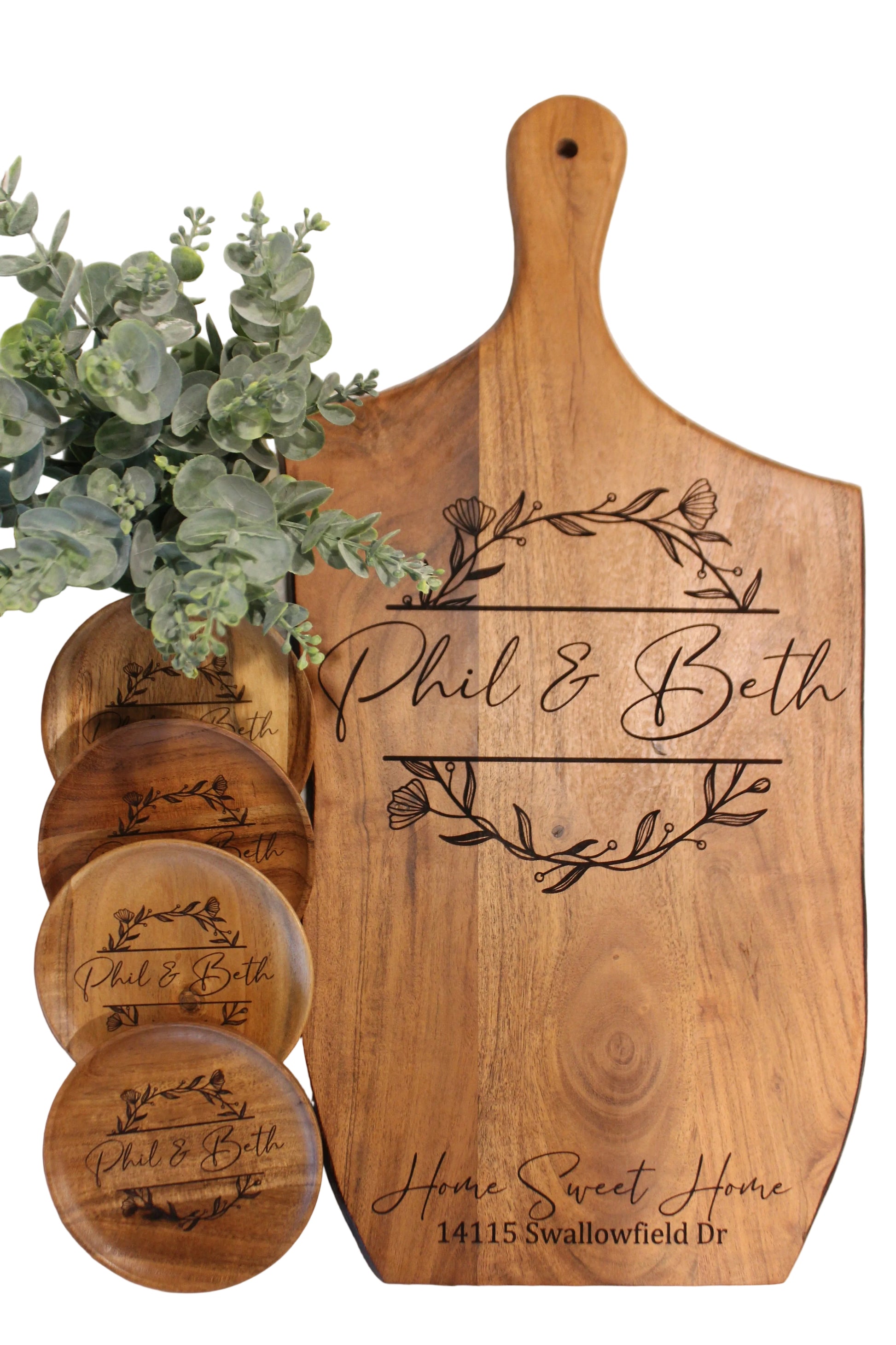 Wooden cutting board and coasters with engraved text on a marble surface